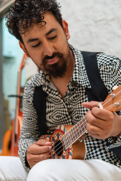 istock A Hispanic Latin musician playing his ukulele in the sofa. 1410210234