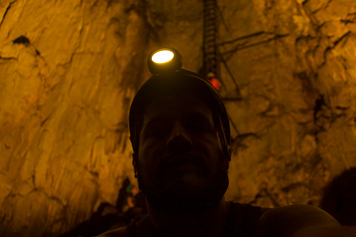 man wearing helmet and spotlight in a deep cavern in Costa Rica