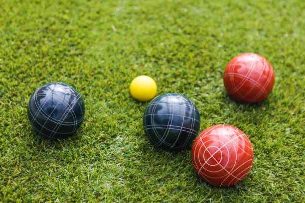 Red, yellow and black bocce balls rest on the grass.