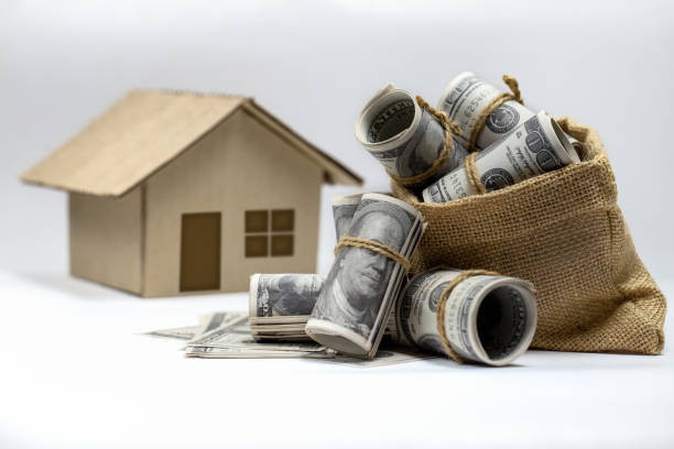Roll of 100 US dollar bills Overflowing hemp sack and a house model on background. stock photo