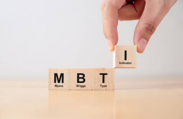 Hand puts wooden cubes with MBTI, Myers-Briggs Type Indicator on table. stock photo