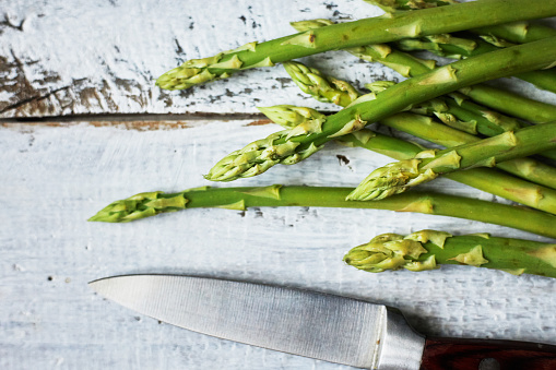 knife and fresh asparagus on wooden table