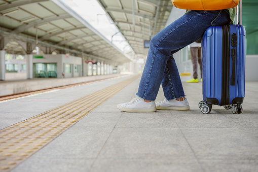 Woman sitting on the bag and waiting at the platform in sky train station.