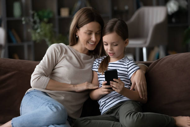istock Interested mom watch tween daughter play game on modern smartphone 1410223355