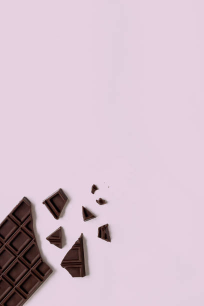 istock Broken chocolate bar on the pink background with copy space 1410224217