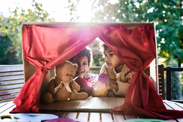 Photo of Happy black kids having a puppet show on a terrace.