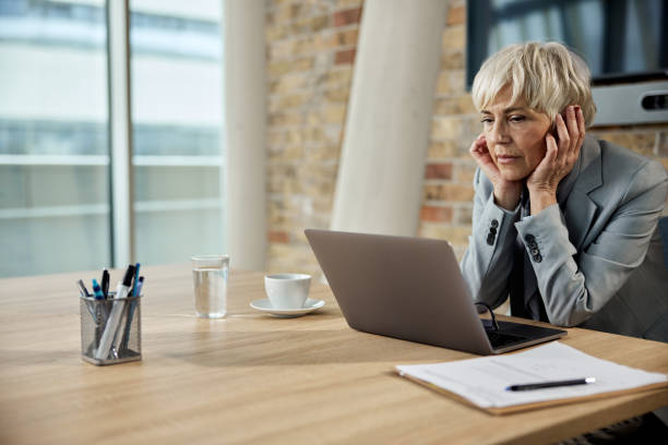 istock Mature female entrepreneur reading an e-mail on a computer in a modern office. 1410225010