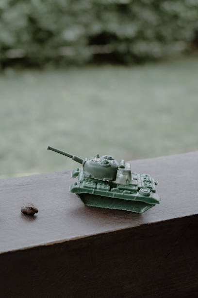 детский игрушечный танк рядом с осколком боевого снаряда - взрыв населения стоковые фото и изображения
