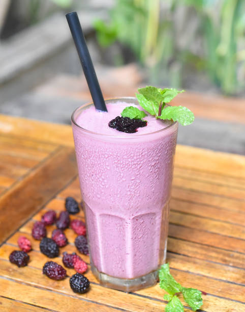 Mulberry smoothie on wooden table with berries closeup stock photo