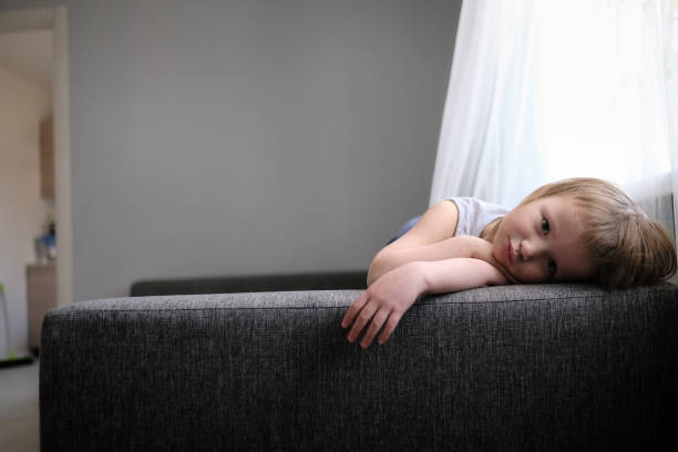 istock Sad kid is bored on couch in living room. 1410229466