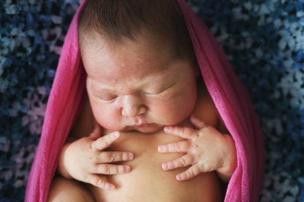 istock tender newborn baby wrapped pink ,sleeping on dark 1410230133