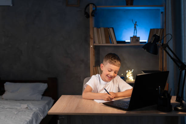 istock boy is doing homework using a laptop computer at his bedroom desk at night 1410231430