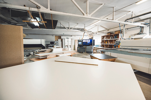 Inside a furniture manufacturing workshop. Special equipment and plenty of chipboard.