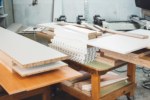 White furniture boards laid on the tables inside a furniture manufacturing firm.