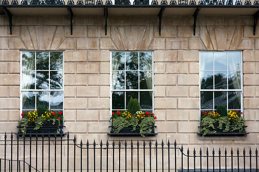 Georgian window triptych. Detail of windows with window boxes and wrought iron railings on facade of generic Georgian building.