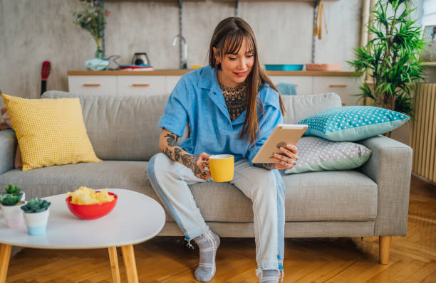 istock Tattooed woman drinking coffee and using digital tablet 1410245356
