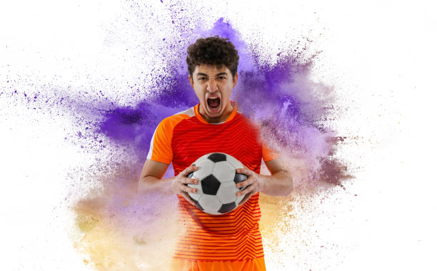 istock Creative sport collage with young man, professional soccer player setting to win isolated on white background with powder splash. Victory, energy, sport. Bright emotions 1410246575