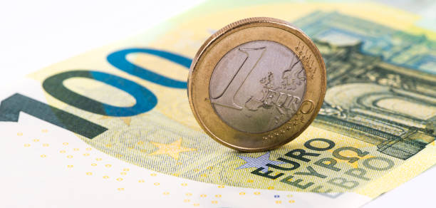 1 euro vor dem hintergrund einer banknote von 100 euro - ein euro stock-fotos und bilder