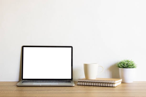 istock Mock up computer with notebook, coffee cup and green leaves over the wooden table. 1410248773