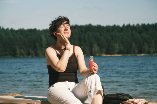Woman is applying sunscreen lotion onto her face