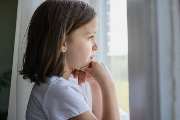 istock Girl looking through the window 1410251122