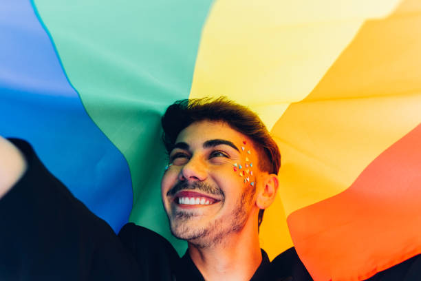 happy gay with rhinestones under lgbt flag - flag rainbow gay pride flag gay man imagens e fotografias de stock