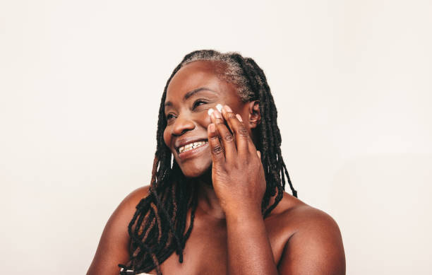 istock Cheerful black woman applying moisturizing cream on her face 1410253363