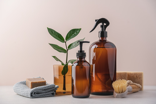 Eco detergents in glass bottles, brushes, rags and sponges on white background