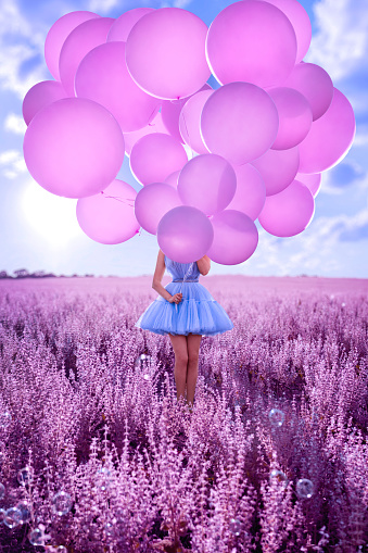 Beautiful woman with pink balloons in lavender field