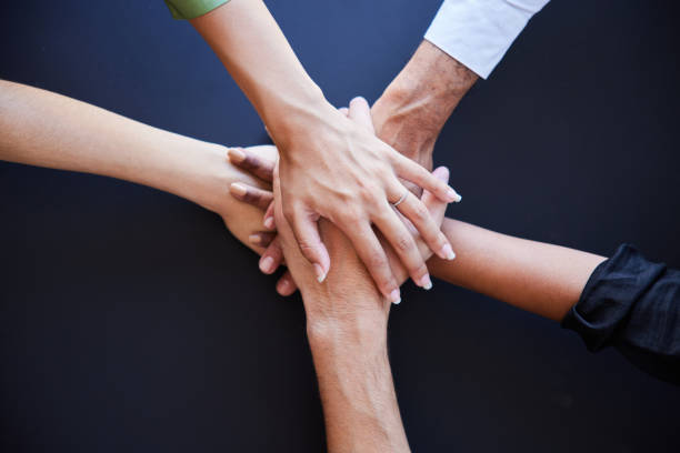 istock Businesspeople sitting at a table with their hands stacked together 1410258132