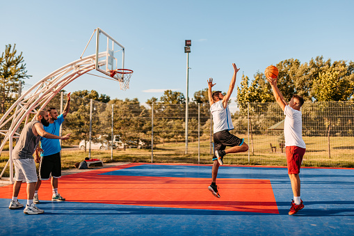 Group of friends playing basketball on a basketball court outdoors.