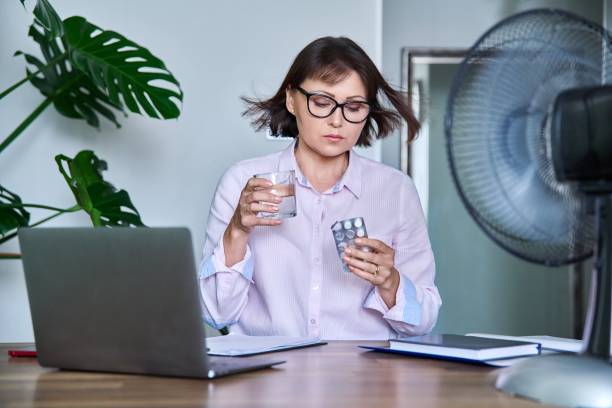 Mature woman with glass of water blister of pills taking medicine stock photo