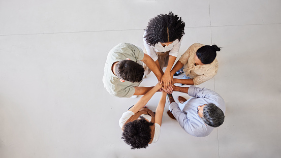 High angle view of a diverse group of businesspeople standing with their hands together in a huddle