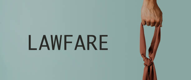the text lawfare and the hand of a man holding a brown blindfold on a gray background, playing with the concept that justice must be blind, in a panoramic format to use as web banner
