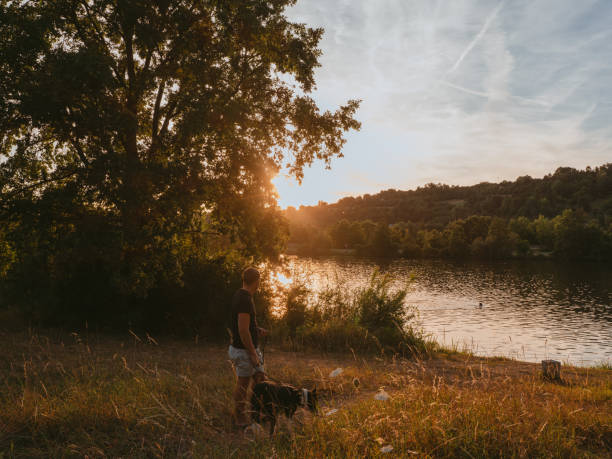 istock Man and his dog outdoors by a river at sunset in summer 1410262539