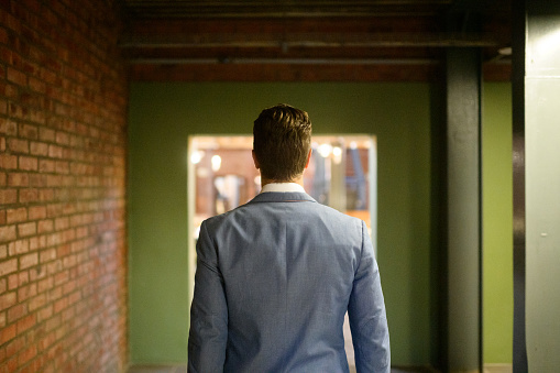 Rear view waist up Business Casual dressed business man walking in corridor