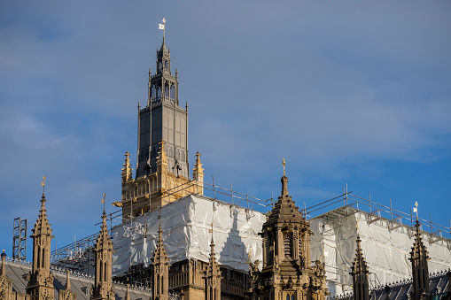 The towers of The Houses of Parliament in Westminster, London, England.  They have recently been refurbished and have spent 3 years hidden behind scaffolding, the newly cleaned building is looking exceptionally bright but there is still work ongoing as seen by the scaffolding and protective sheeting..