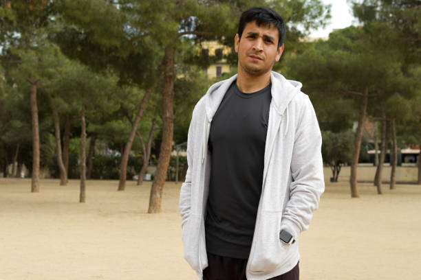 peruvian feature man dressed in white hoodie standing in outdoor place while looking at camera