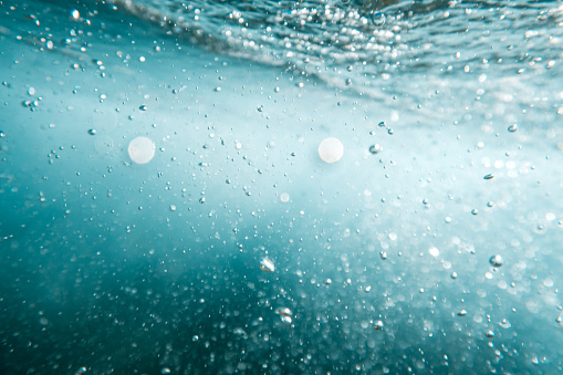 Underwater View of Bubbles In Deep Blue Ocean. Close Up Water. Background