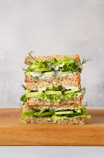 English tea cucumber sandwiches with cream cheese, dill on light gray background. Close up. Vertical format.