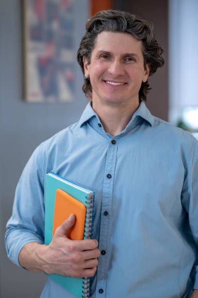 istock Smiling man in a blue shirt with tablet and notebook 1410273294