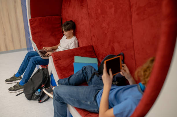 istock Two school boys feeling comfortable in the lounge zone and doing homework 1410273315