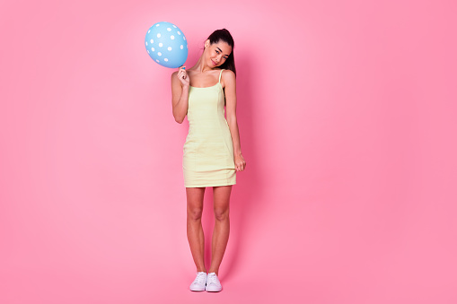 Full length photo of sweet charming woman wear yellow dress holding dotted balloon empty space isolated pink color background.