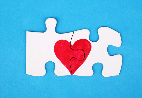 Jigsaw puzzle pieces in form of heart on blue background. Love, charity, donation, helping concept. Perfect match, reunion.