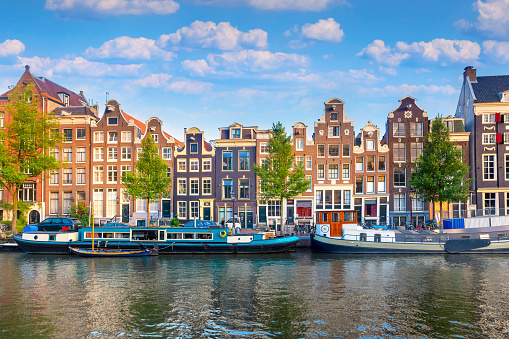 Amsterdam. Panoramic view of the historic city center of Amsterdam. Traditional houses and bridges of Amsterdam. An early quiet morning and the serene reflection of houses in the water. A European journey to a historic town. Europe, Netherlands, Holland, Amsterdam.
