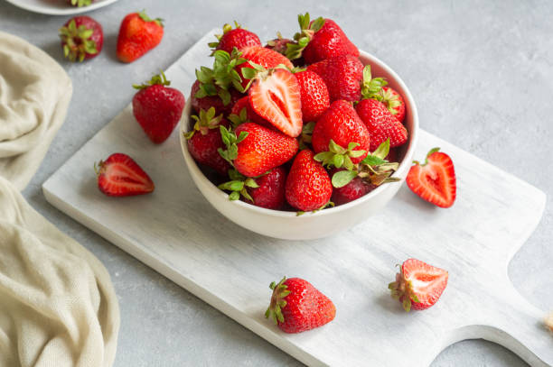 istock Fresh ripe strawberries in white bowl on white cutting board on rustic table, red summer fruit 1410278875
