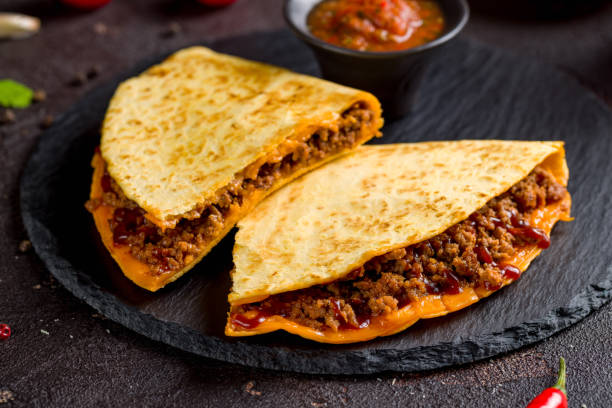 istock Quesadilla with beef, cheese, bbq sauce and sauces on dark stone plate macro close up 1410279231