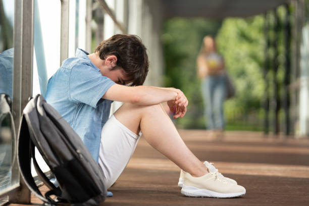 Sad teenager boy sitting in a corridor Sad teenager student boy sitting in a corridor. Depression and anxiety concept low self esteem stock pictures, royalty-free photos & images