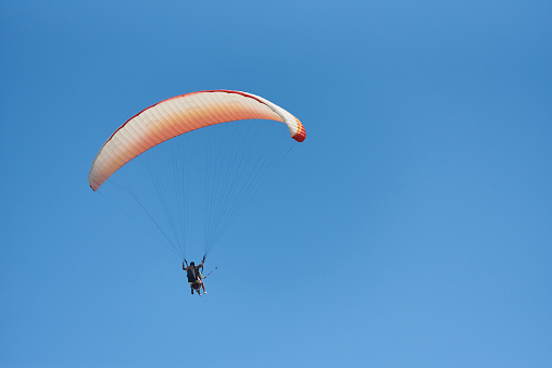 Paragliding tandem with tourist in blue sky.
