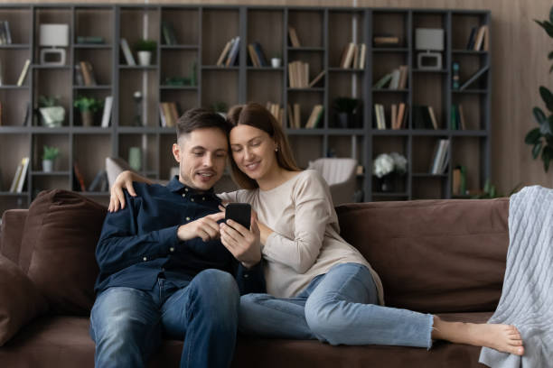 istock Happy affectionate millennial family couple using smartphone applications. 1410282355